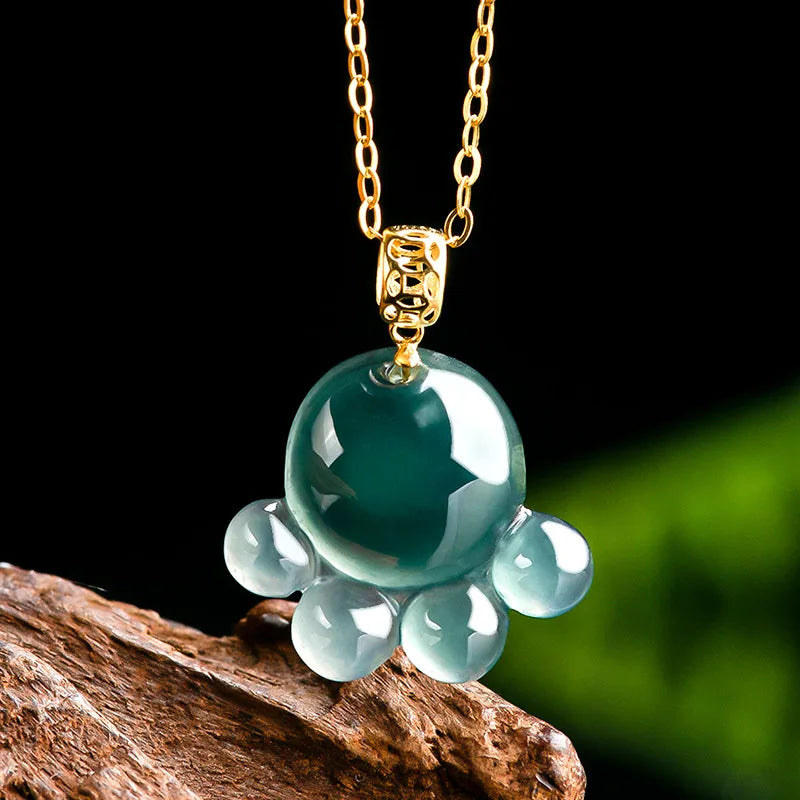 Green jade pendant on a gold chain with a dark background