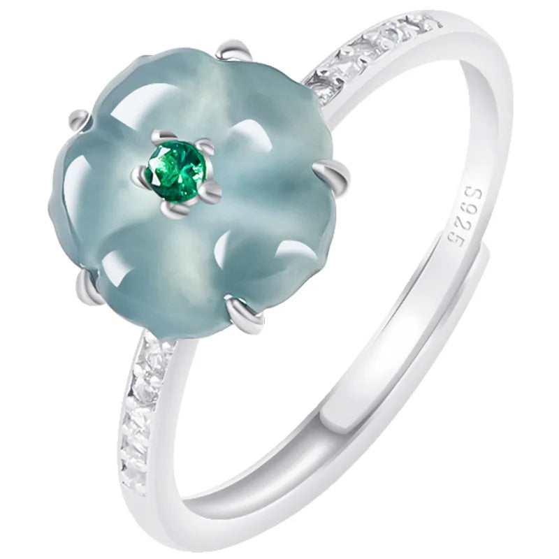 Silver ring with a green gemstone and diamond accents on a white background
